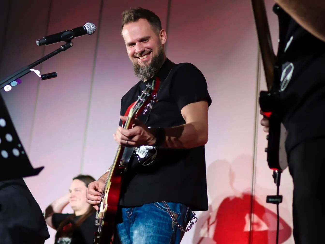 Mężczyzna gra na gitarze i śpiewa na scenie podczas wydarzenia firmowego.