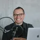Michał Grela, a smiling man in a dark jacket