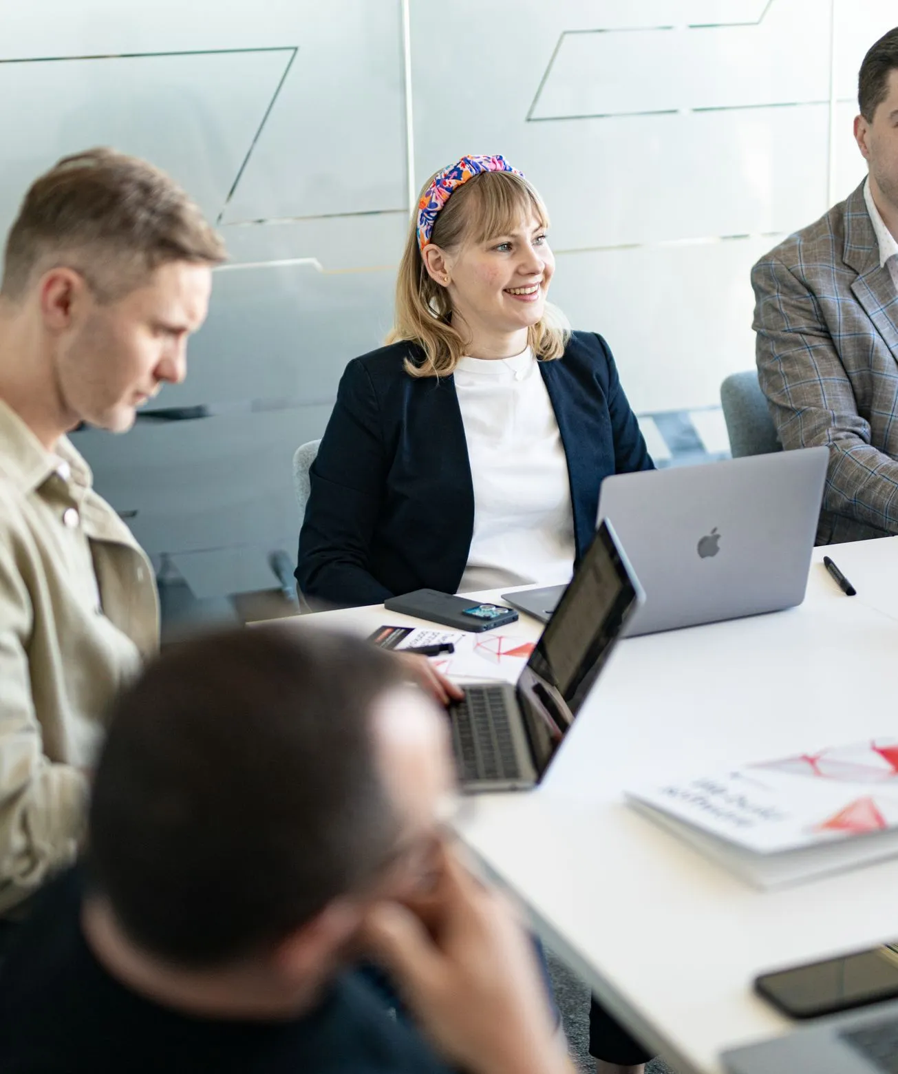 Speednet team members talking at a meeting table with laptops.