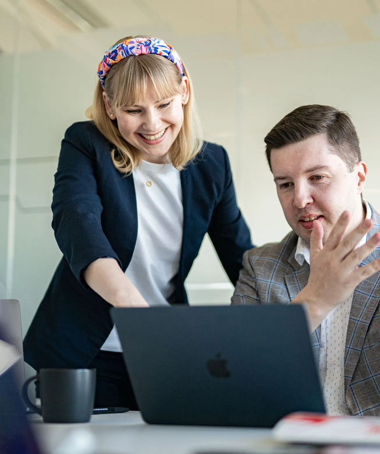 A smiling Speednet team member leaning over a laptop as a colleague explains an idea.