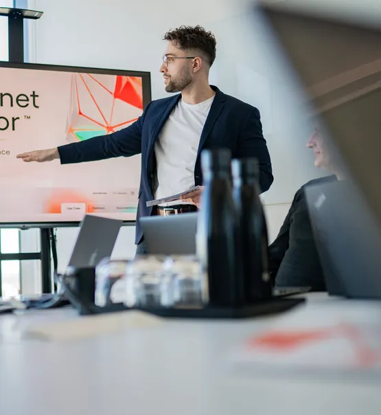 A Speednet team member presenting at a screen during a meeting.