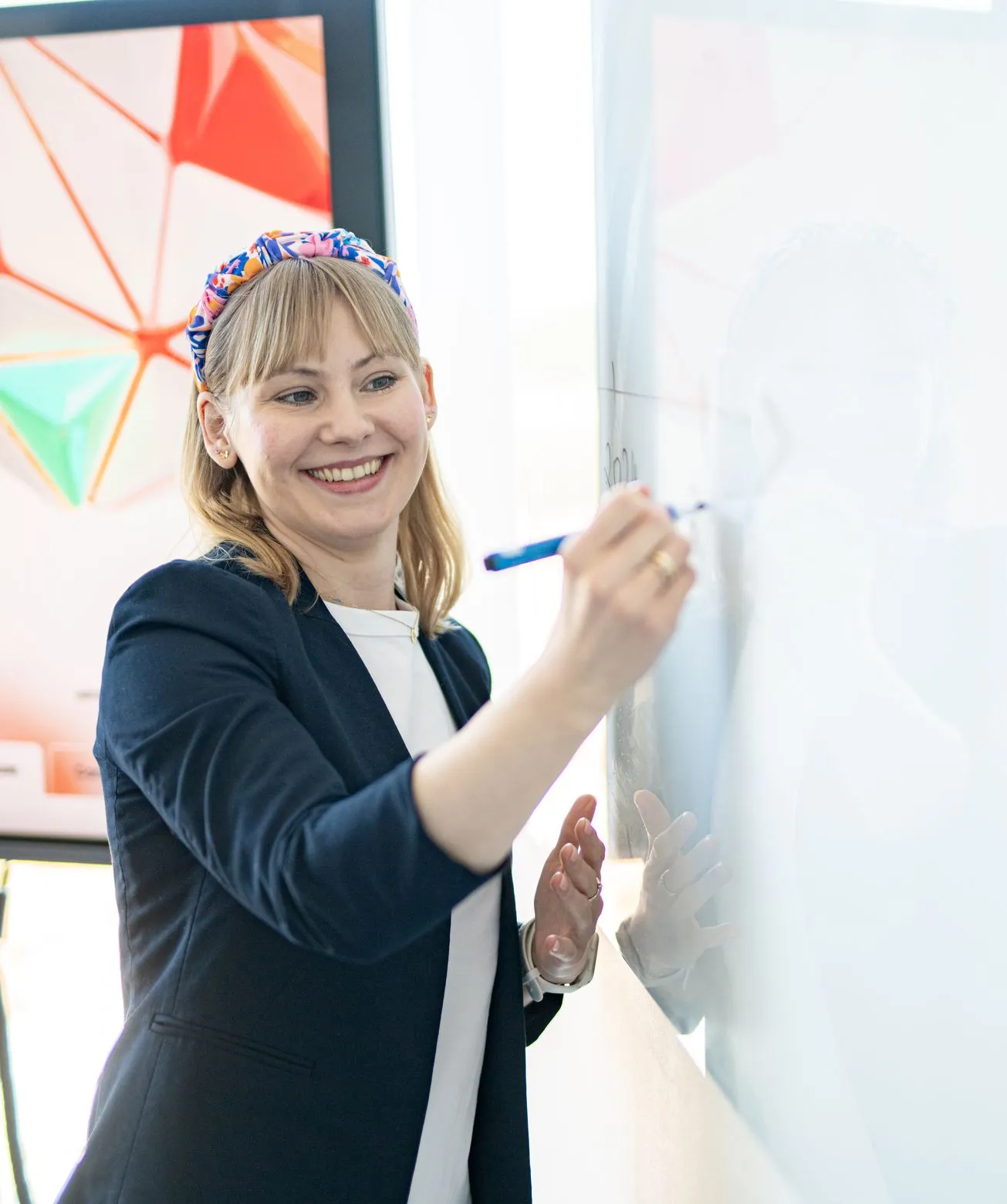 A smiling Speednet team member writing on a glass board during a workshop.