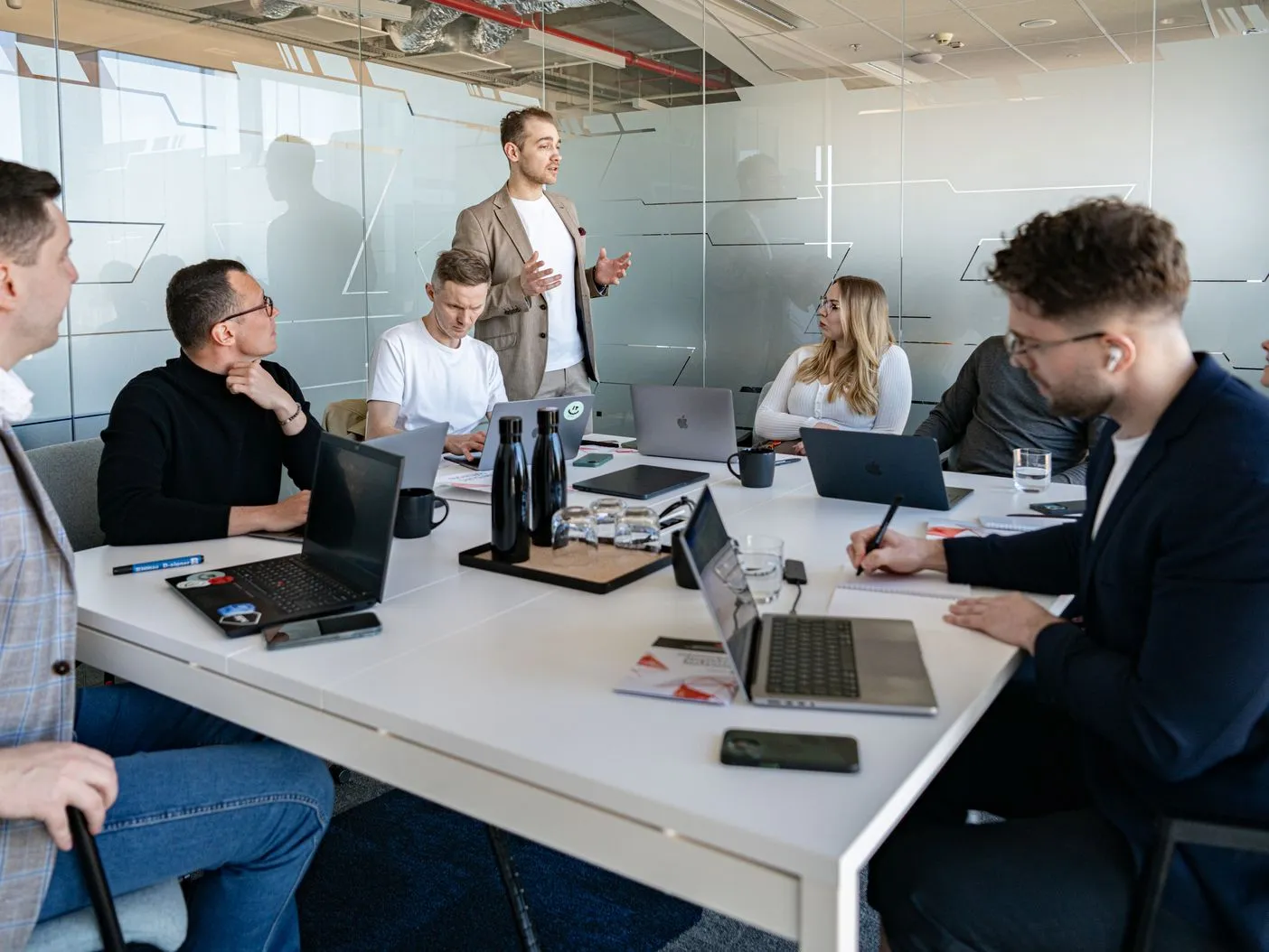 A Speednet team member standing and presenting to colleagues seated around a meeting table with laptops.