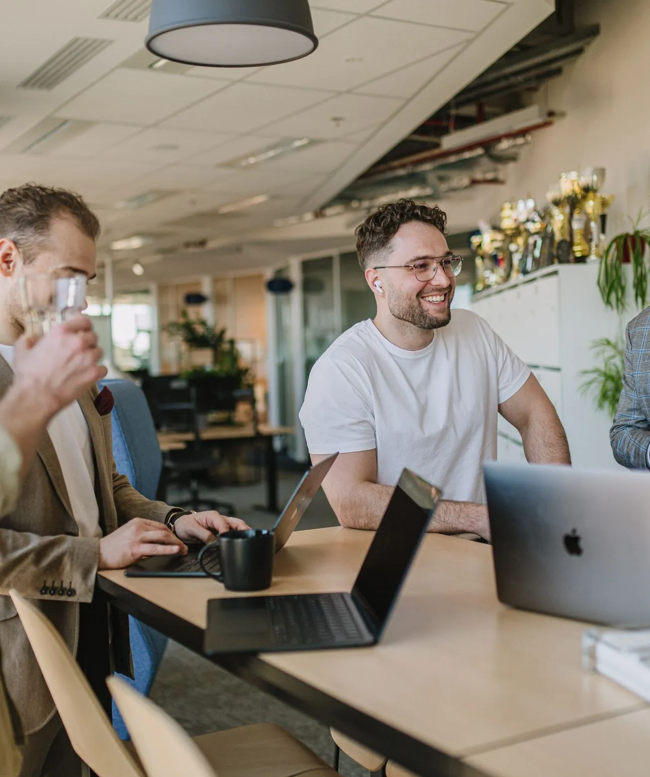 Smiling Speednet team members with laptops at a shared desk in the office.