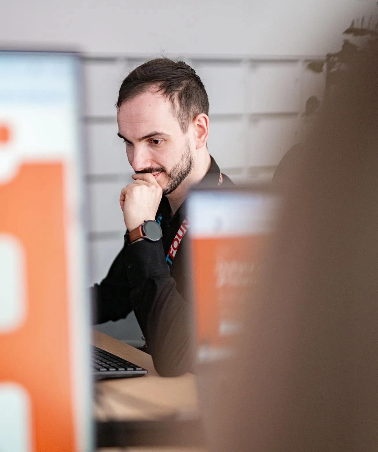 A Speednet developer at a desk, looking thoughtfully at a laptop screen.
