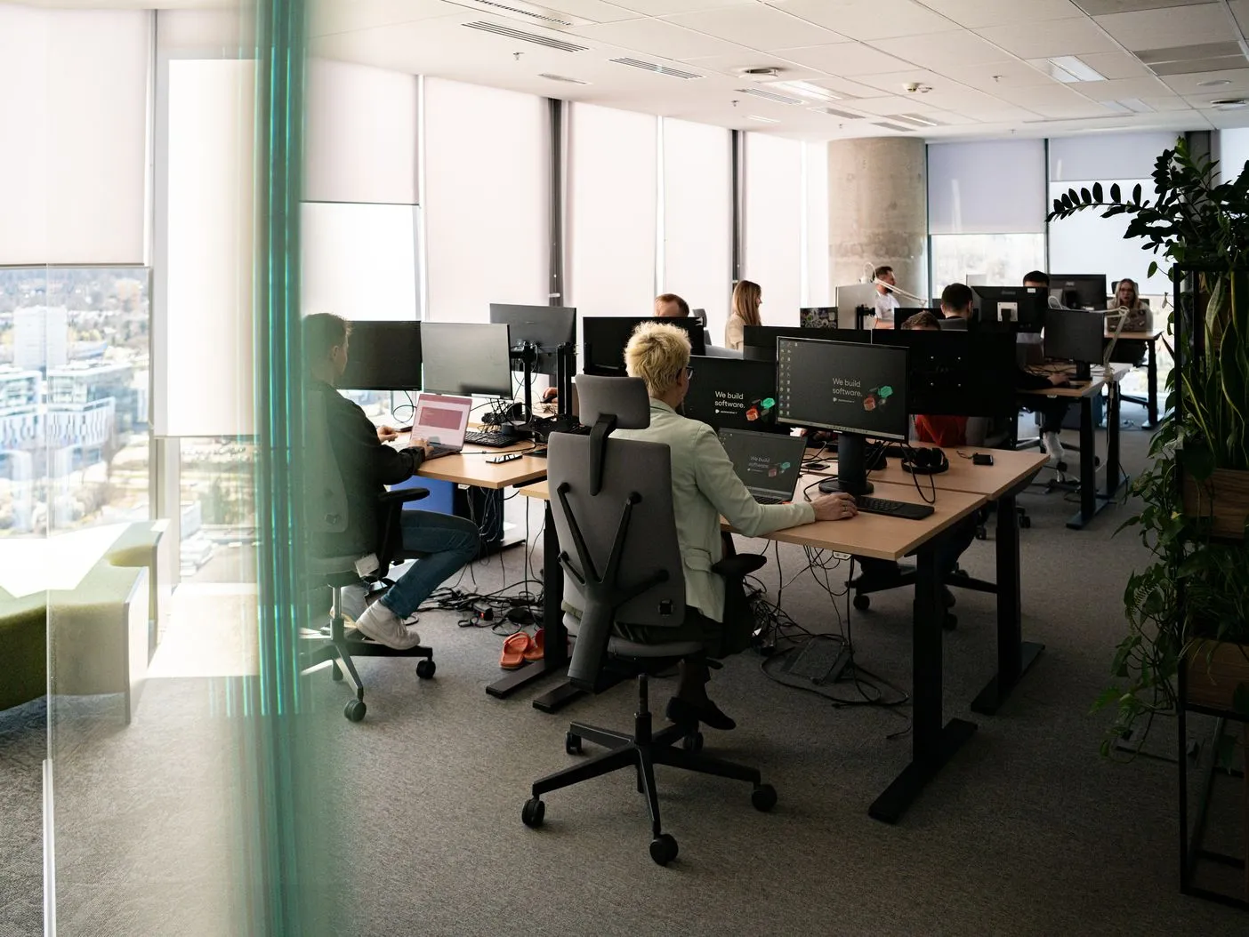 Speednet team members working at desks in an open-plan office, seen through a glass wall.