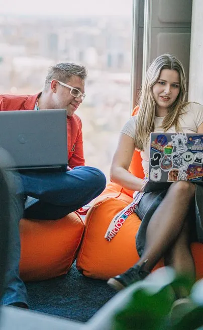 Two Speednet team members working on laptops on beanbags by the window.