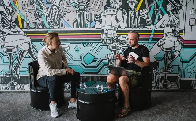 Two Speednet team members talking in lounge chairs in front of a mural.