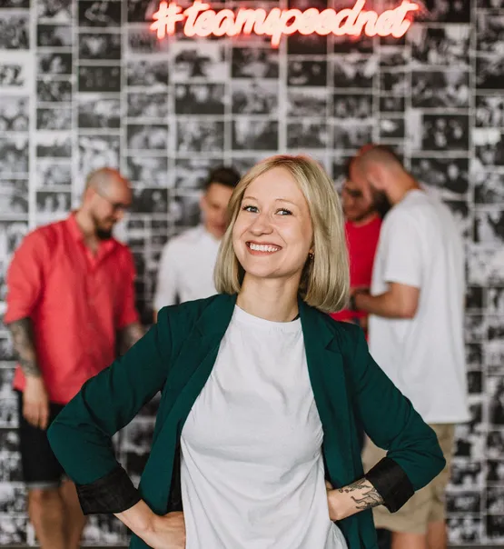 A smiling Speednet team member in a green blazer in front of the