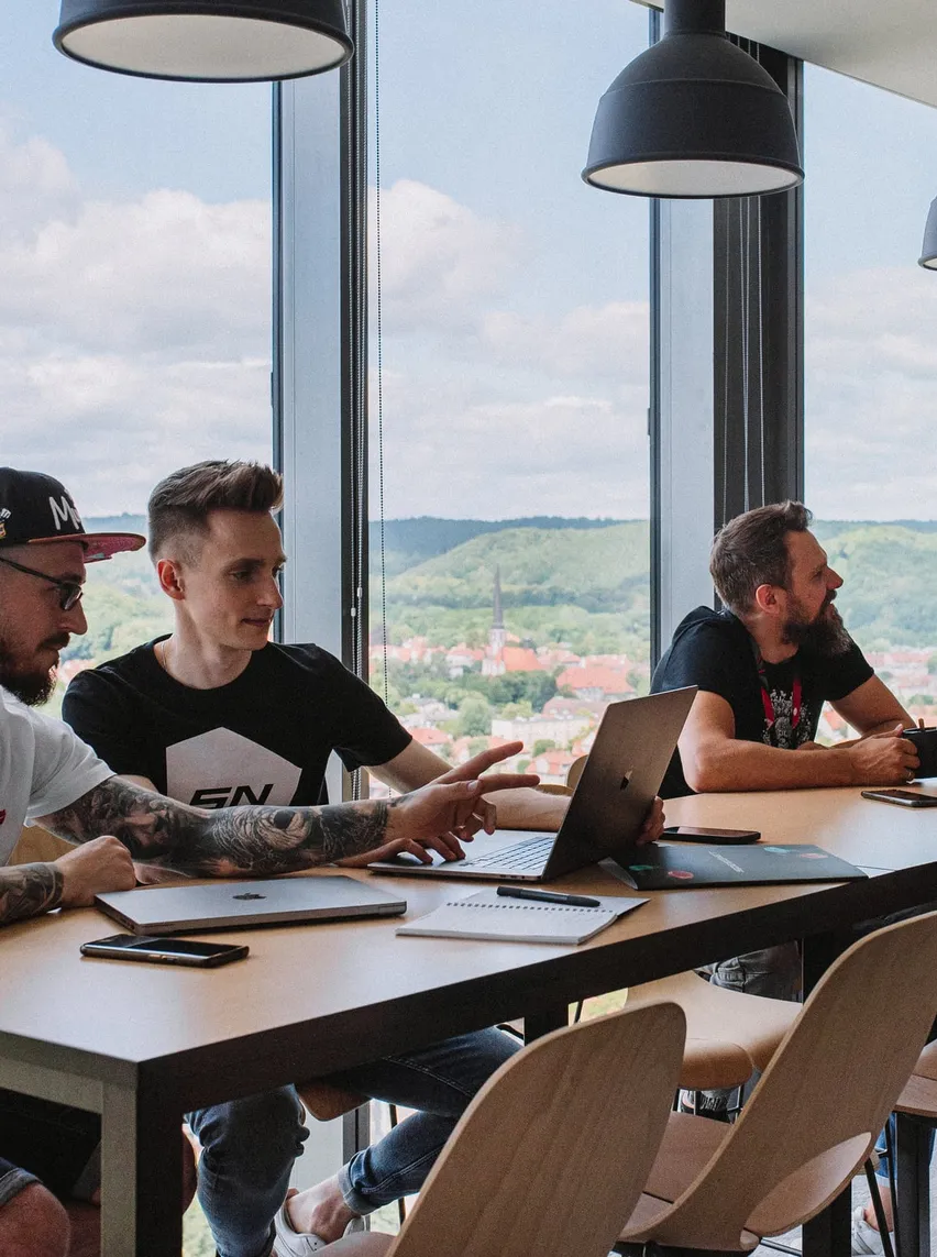 Speednet team members discussing work at a table by the window.