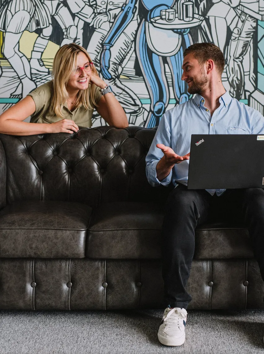 Two Speednet team members talking on a leather couch.